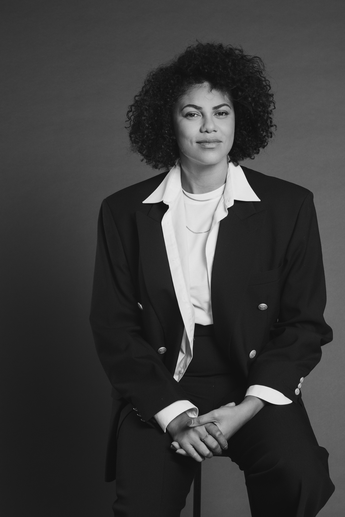 Fashionable Woman in Black Suit Sitting on a Chair